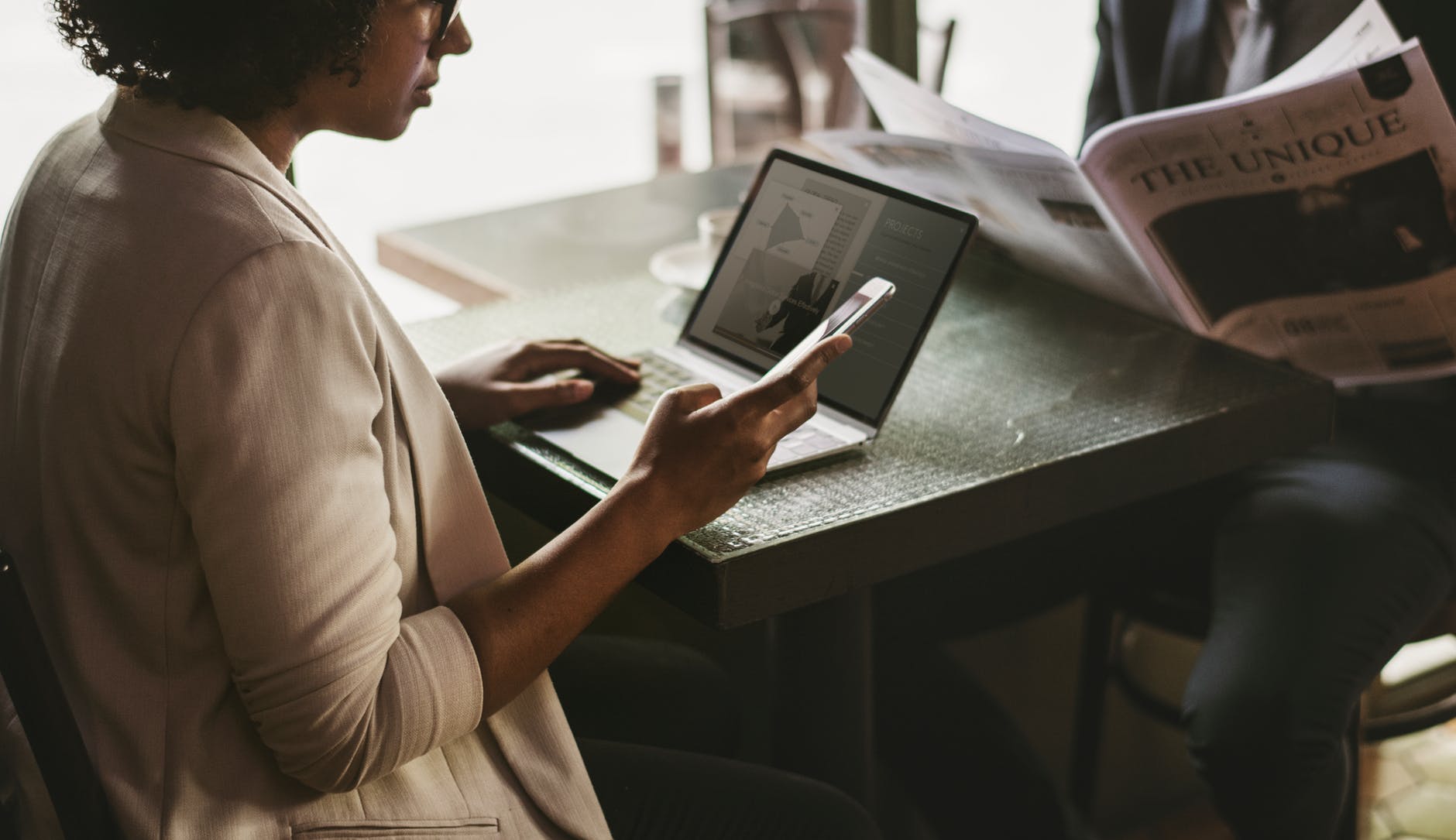 woman using smartphone and laptop near black table
